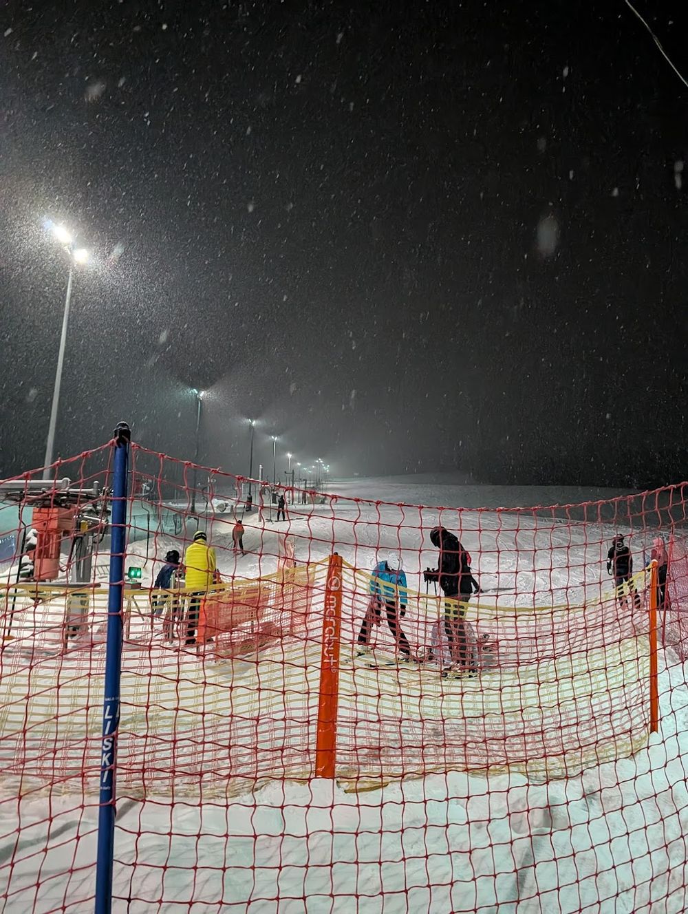 Wieczorne oświetlenie wyciągu narciarskiego w Przygórzu z widokiem na stok.