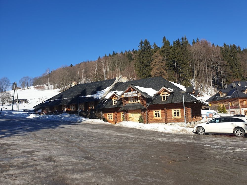 Malownicze schronisko górskie otoczone zaspami śniegu w słoneczny, mroźny dzień.