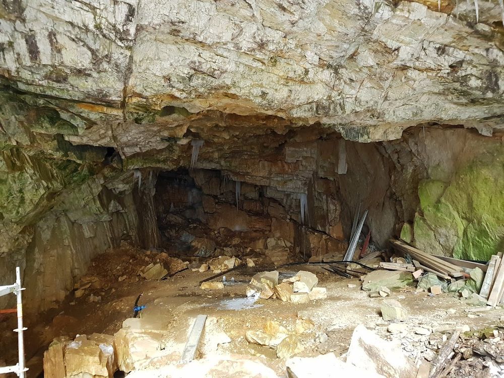 Wejście do małej jaskini skalnej pod niebem o świcie pod słońcem.