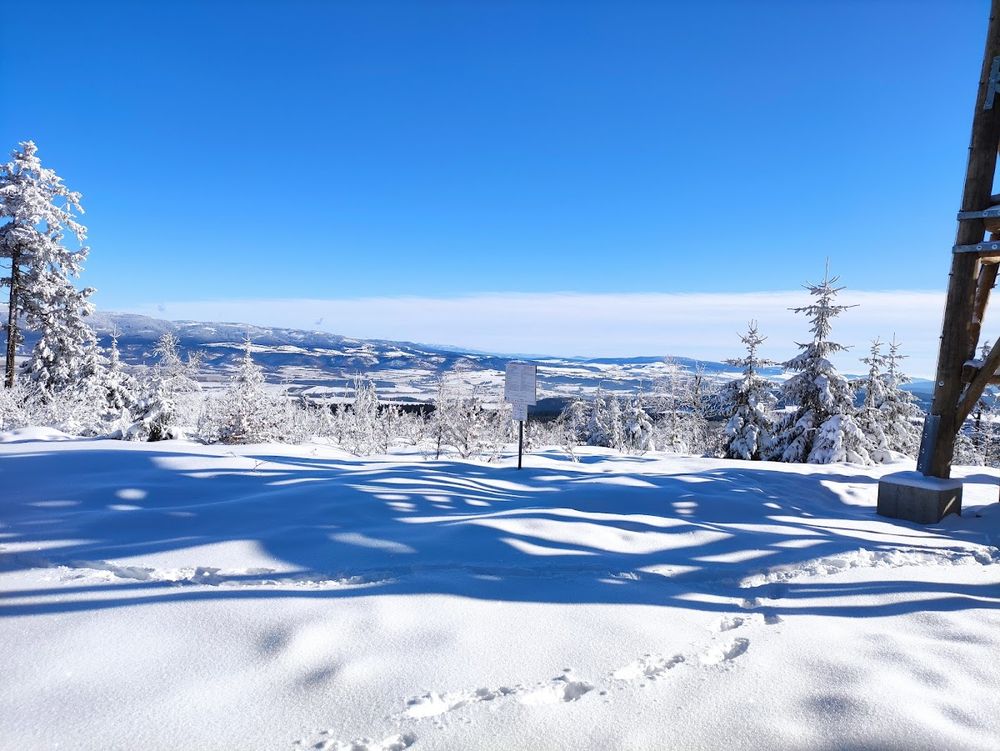 Zimowa panorama Sudetów widziana z wieży na Czerńcu – morze gór pod błękitnym niebem.