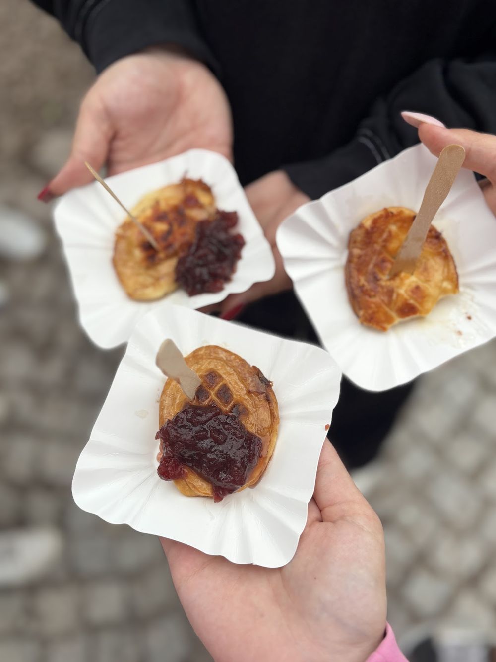 Osoba trzymająca dwie małe kanapki/burgery w rękach.