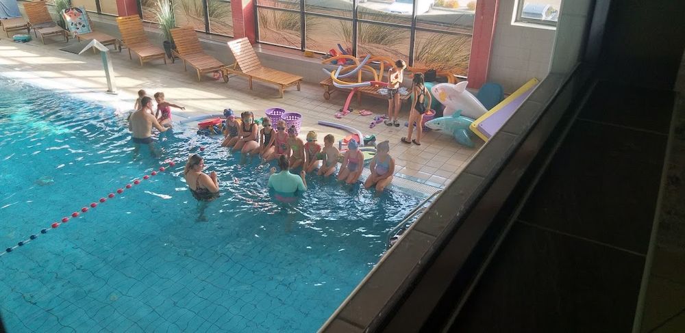 Dzieci bawiące się w basenie, radość i ruch wody.