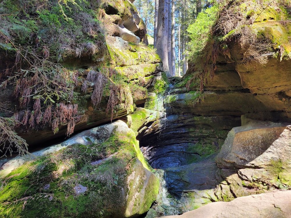 Słoneczna polana w otoczeniu wysokich skał pod niebem pod słońcem.