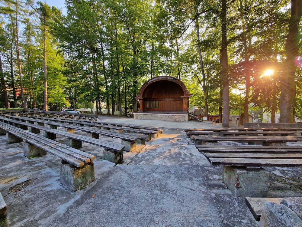 Nastrojowy amfiteatr z rzędami drewnianych ławek przed Muszlą.