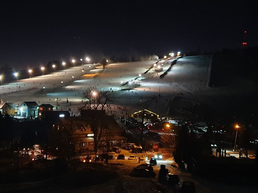 Iluminacja tras narciarskich na Przełęczy Sokolej po zmroku.