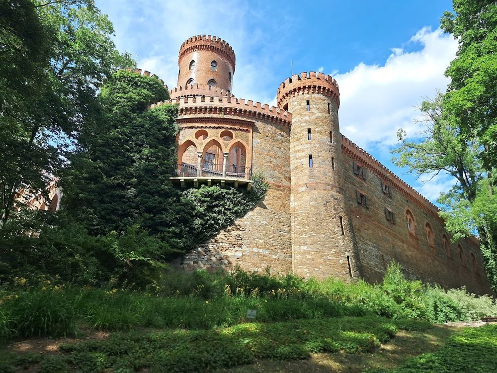 Monumentalna bryła pałacu w Kamieńcu Ząbkowickim pod śnieżną okiścią w pełnym słońcu.
