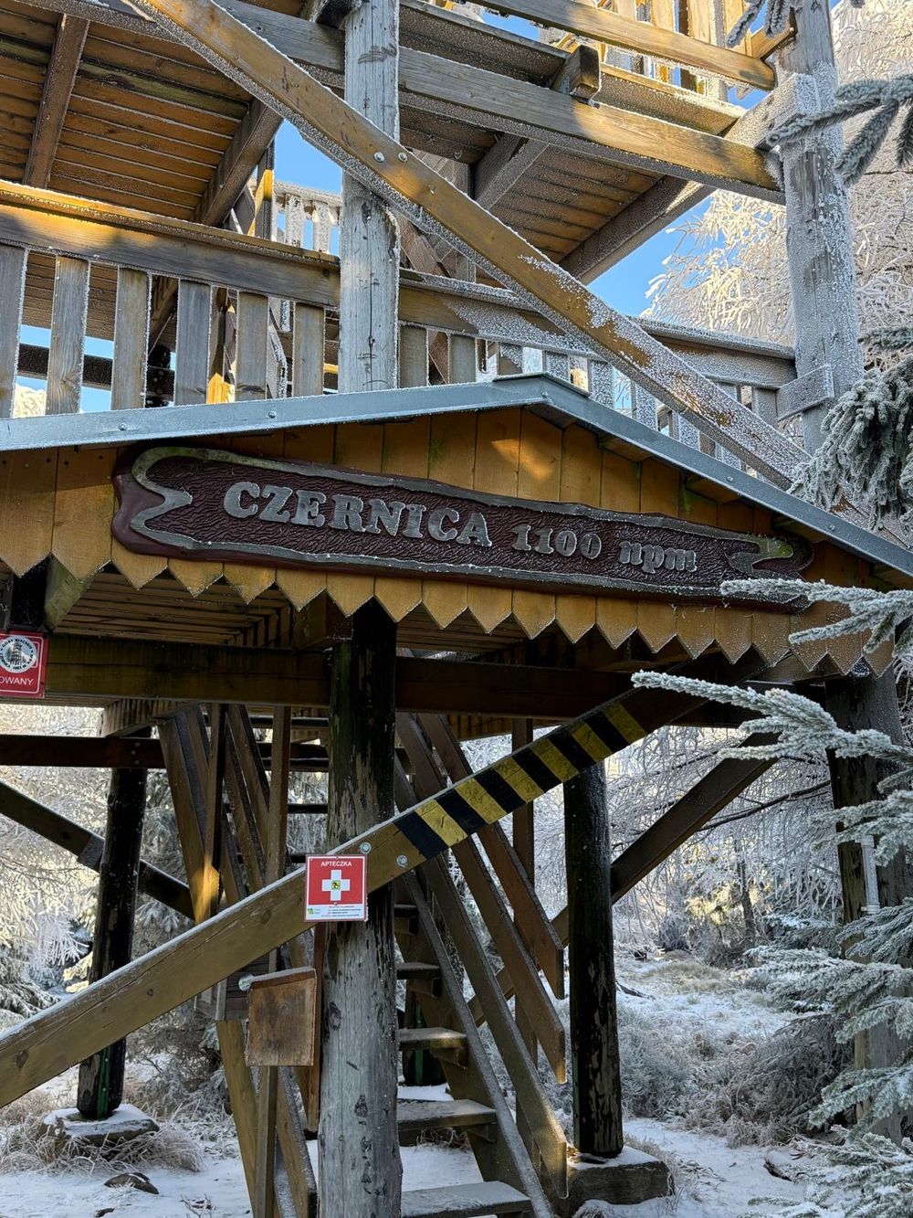 Tabliczka szczytowa na drewnianej konstrukcji wieży.