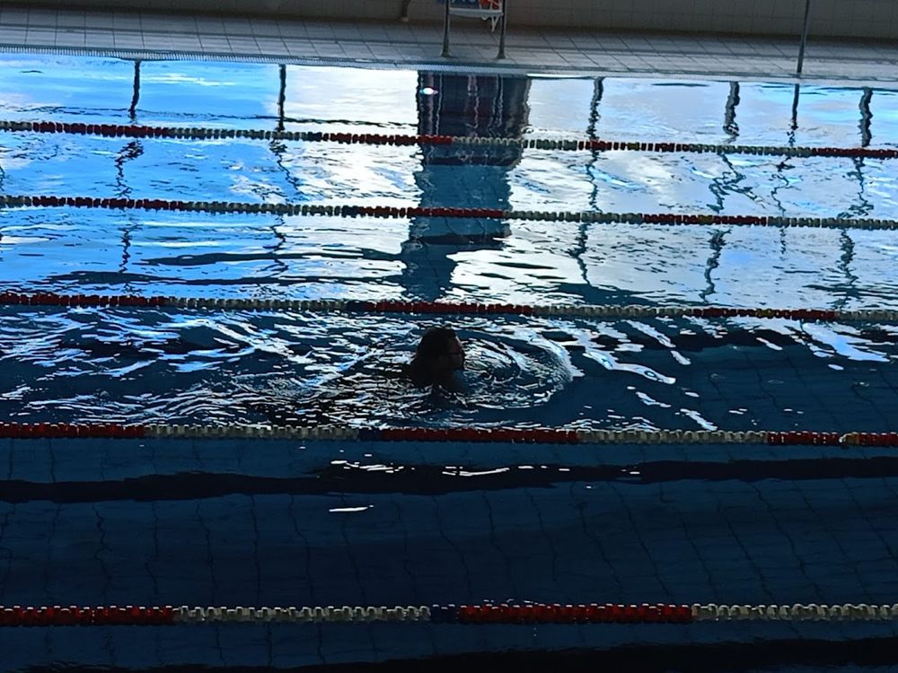 Lustro wody w basenie Aquaparku Granit, odbijające sufit i światła.