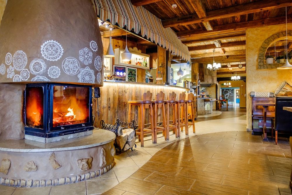 Wnętrze karczmy w Szarotce z nastrojowym kominkiem i drewnianym wykończeniem.