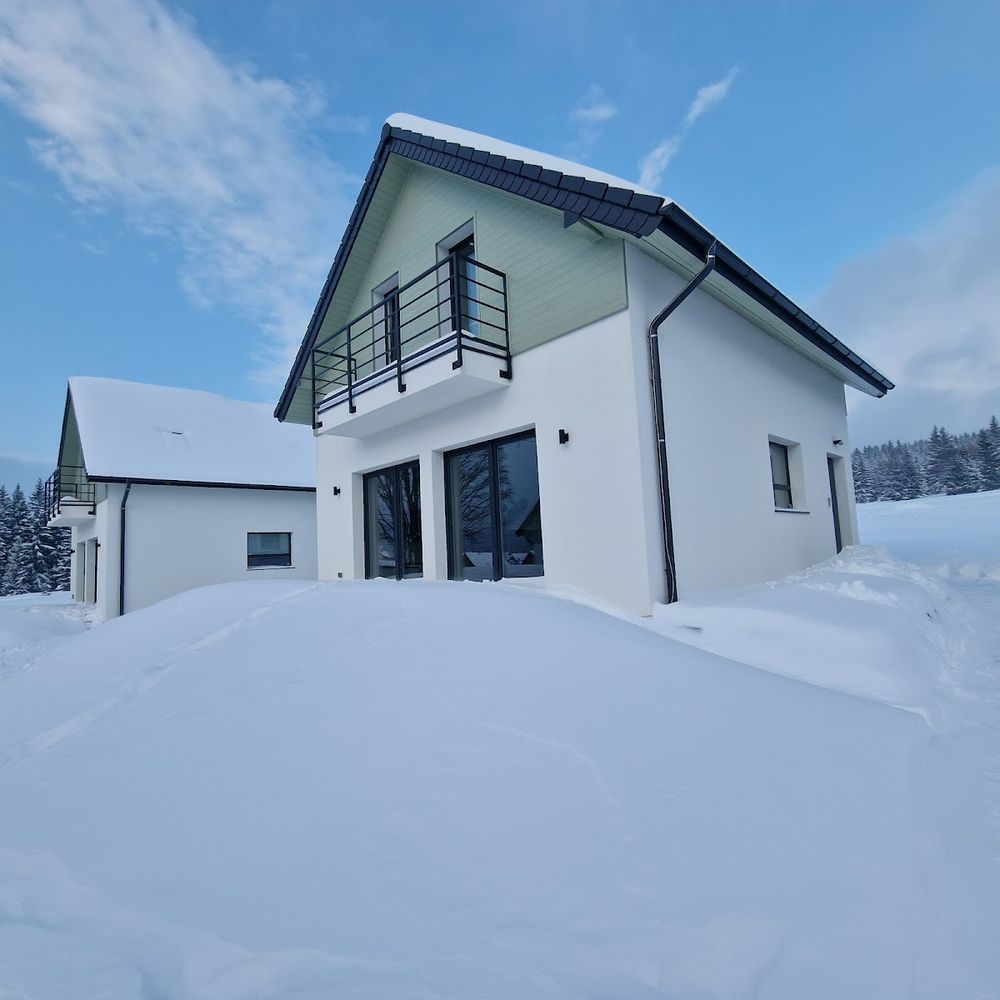 Nowoczesna bryła domu All Season Ski&Bike pod świeżym śniegiem.