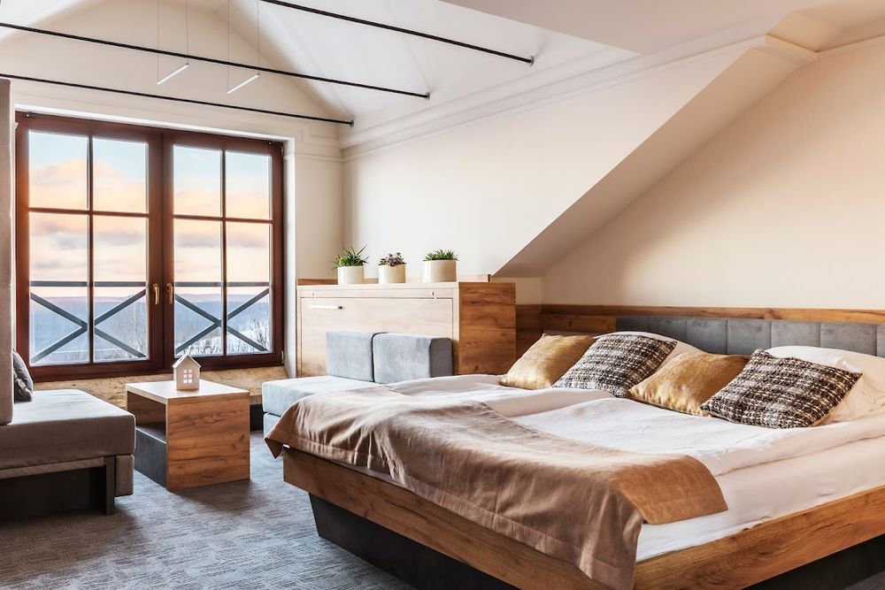 Elegancki pokój na poddaszu Szarotki z drewnianymi skosami.