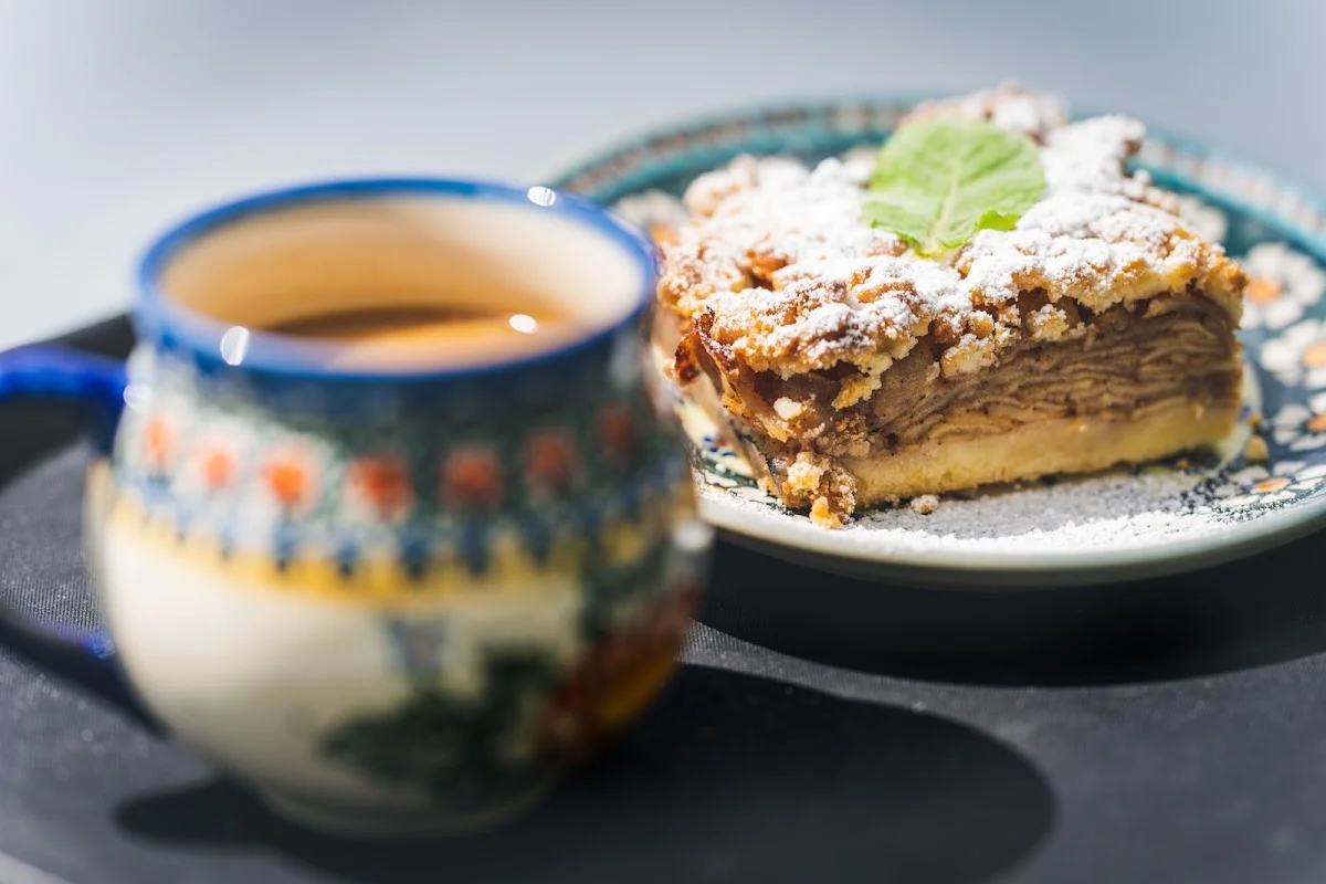 Kawa i kawałek ciasta z kremem w przytulnym wnętrzu.