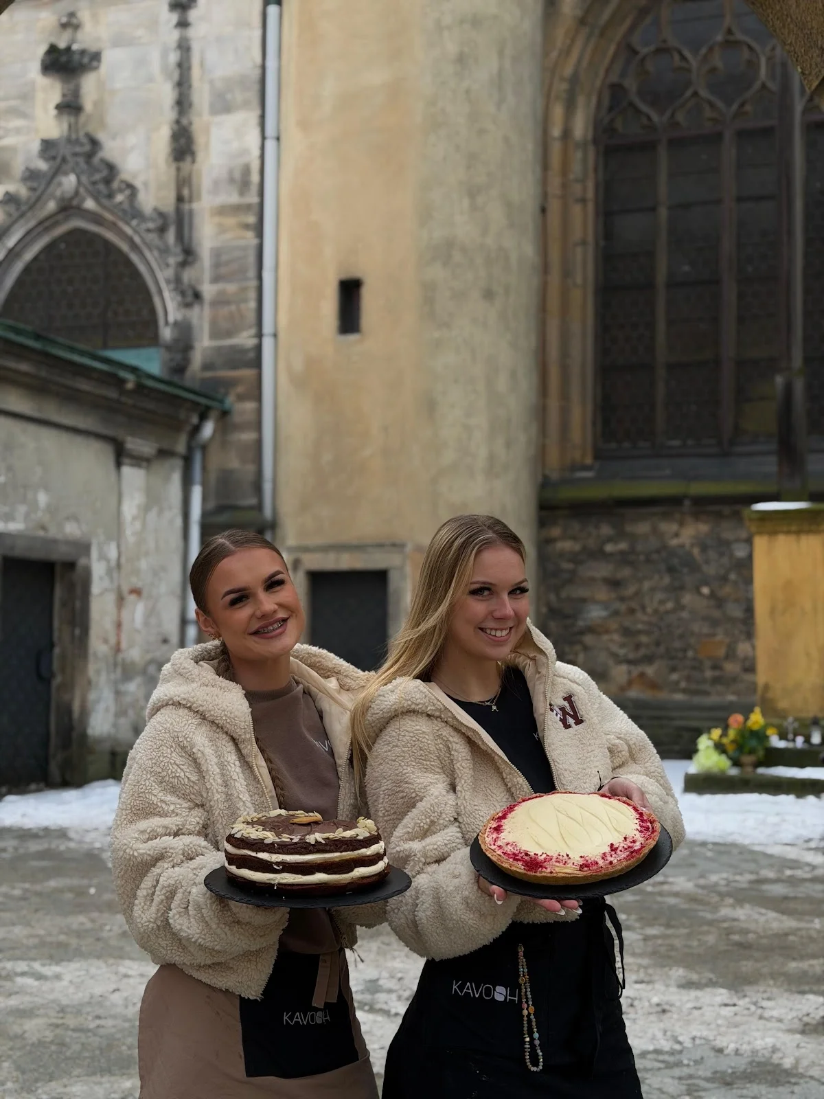 Dwie kobiety niosące ciasta przed starym kościołem.