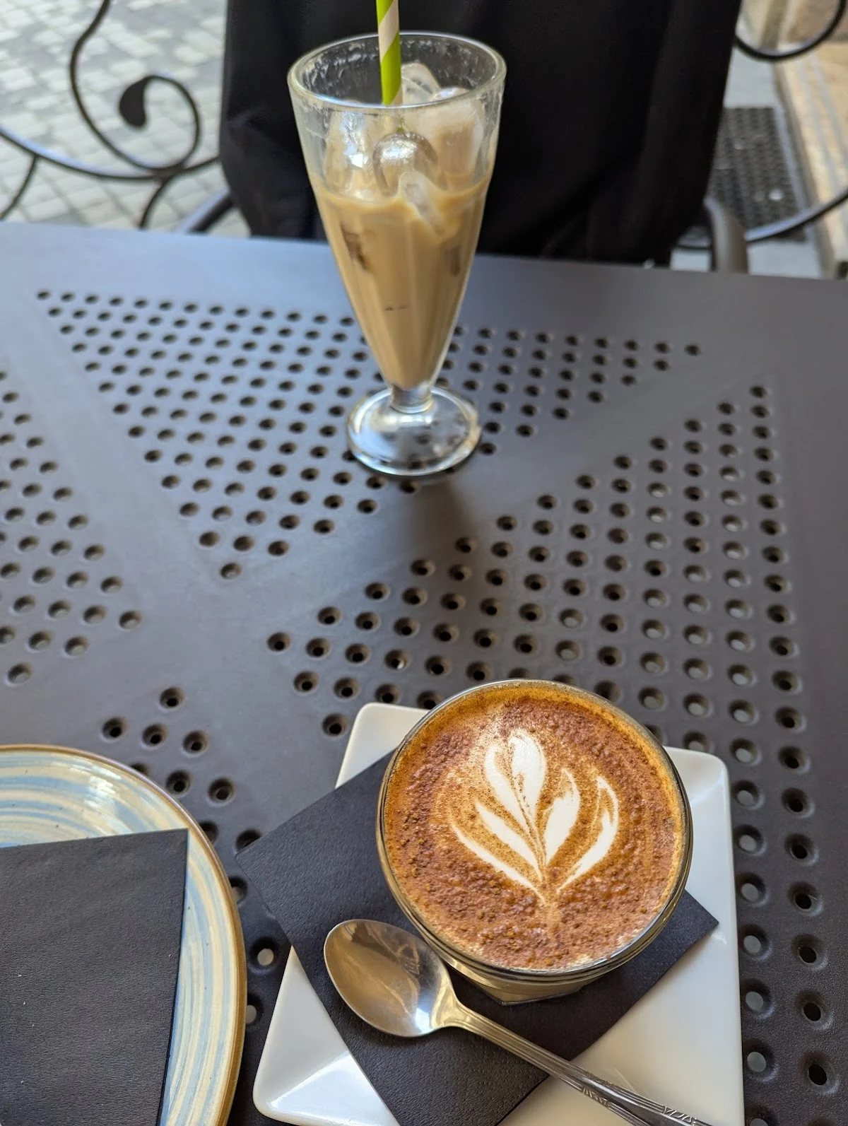 Kawa i szklanka napoju na metalowym stoliku.