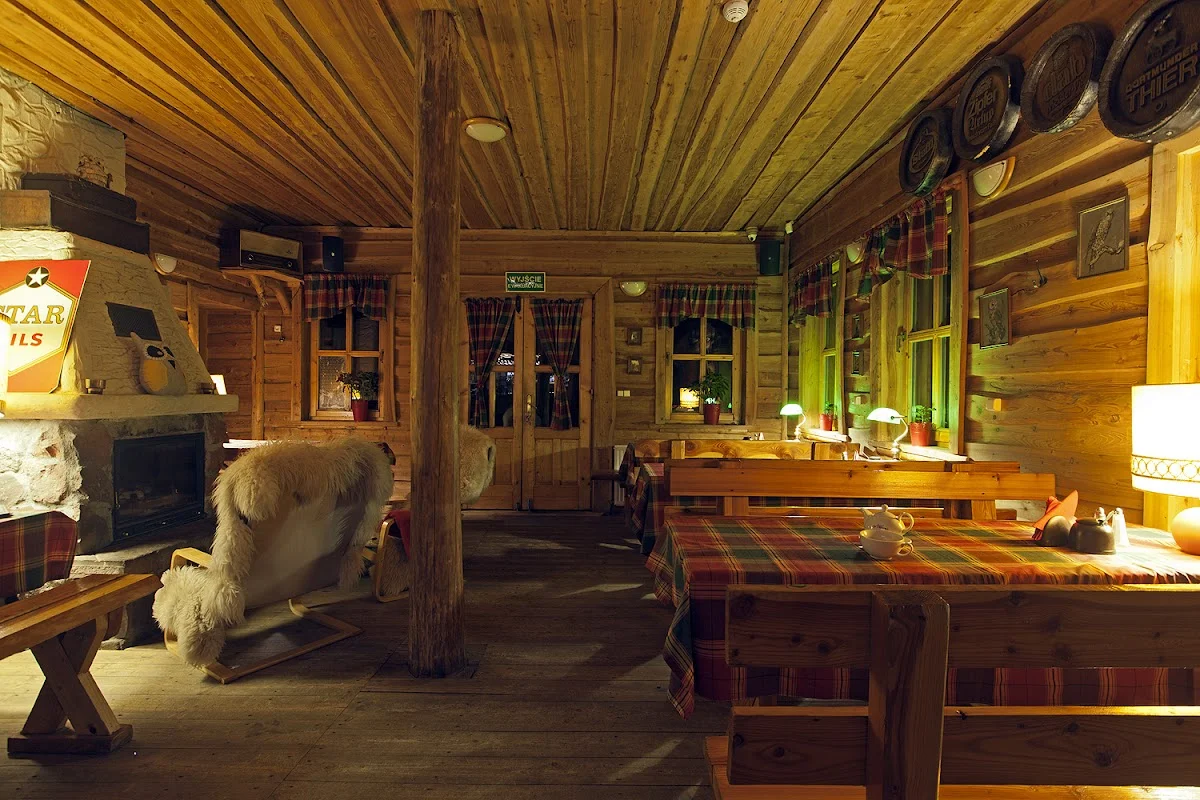 Góralska izba z drewnianymi ławami i stołami.