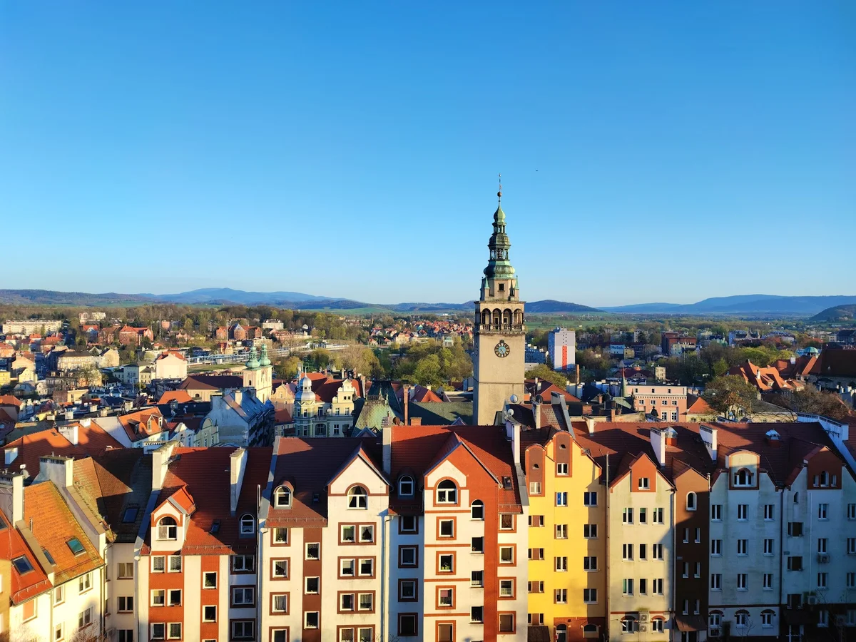 Panorama miasteczka o zachodzie słońca ze złotymi chmurami pod niebem.