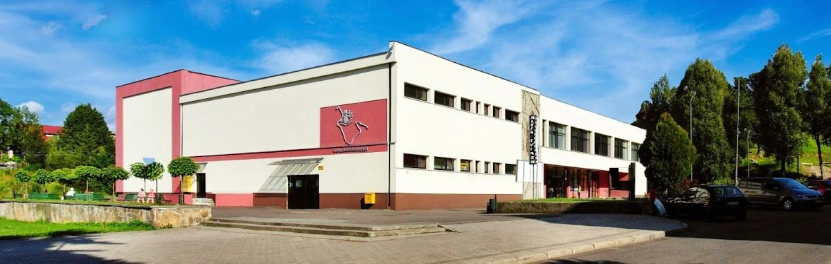 Budynek o charakterze usługowym o jasnej elewacji o zachodzie słońca pod niebem.