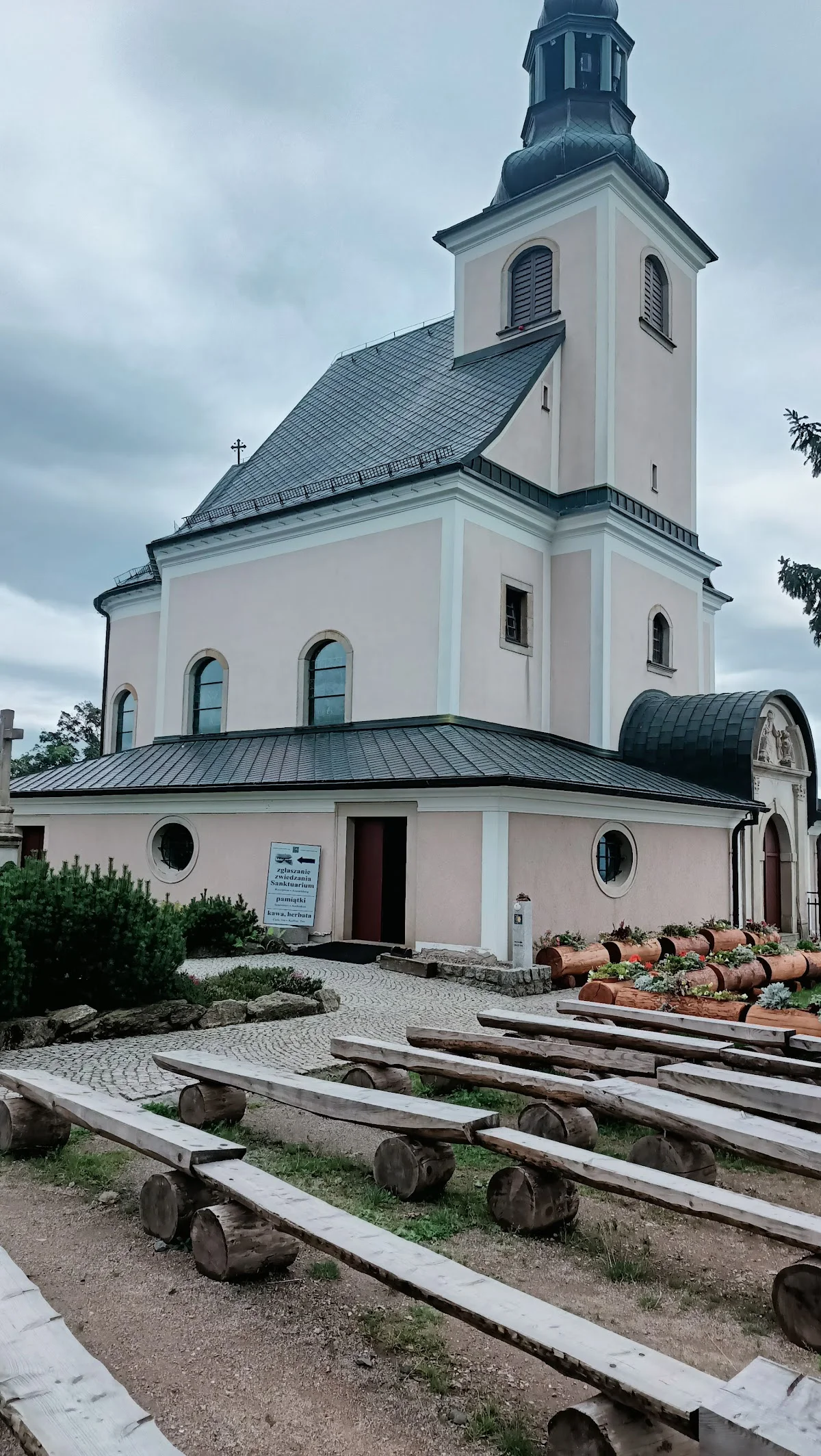 Kościół z wysoką wieżą o barokowej architekturze pod niebem pod słońcem.