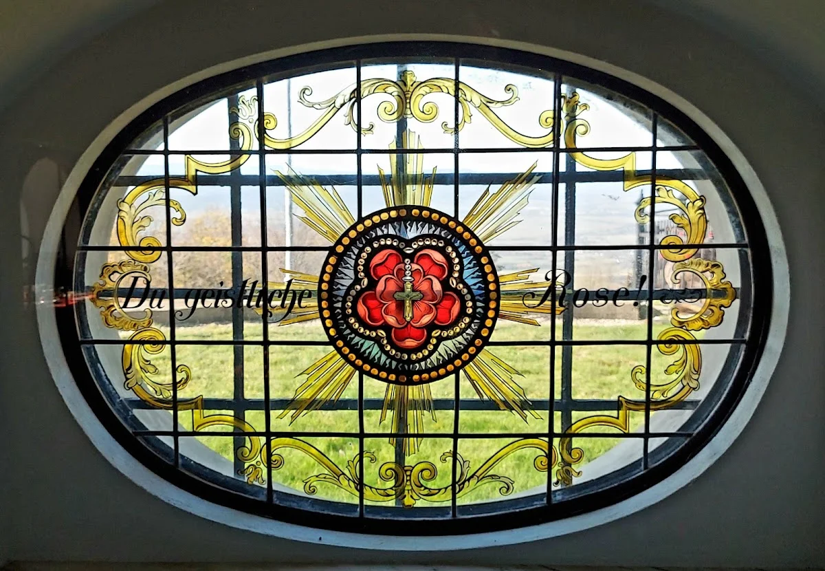 Zabytkowy witraż w okiennym otworze o tradycyjnym wystroju pod słońcem.