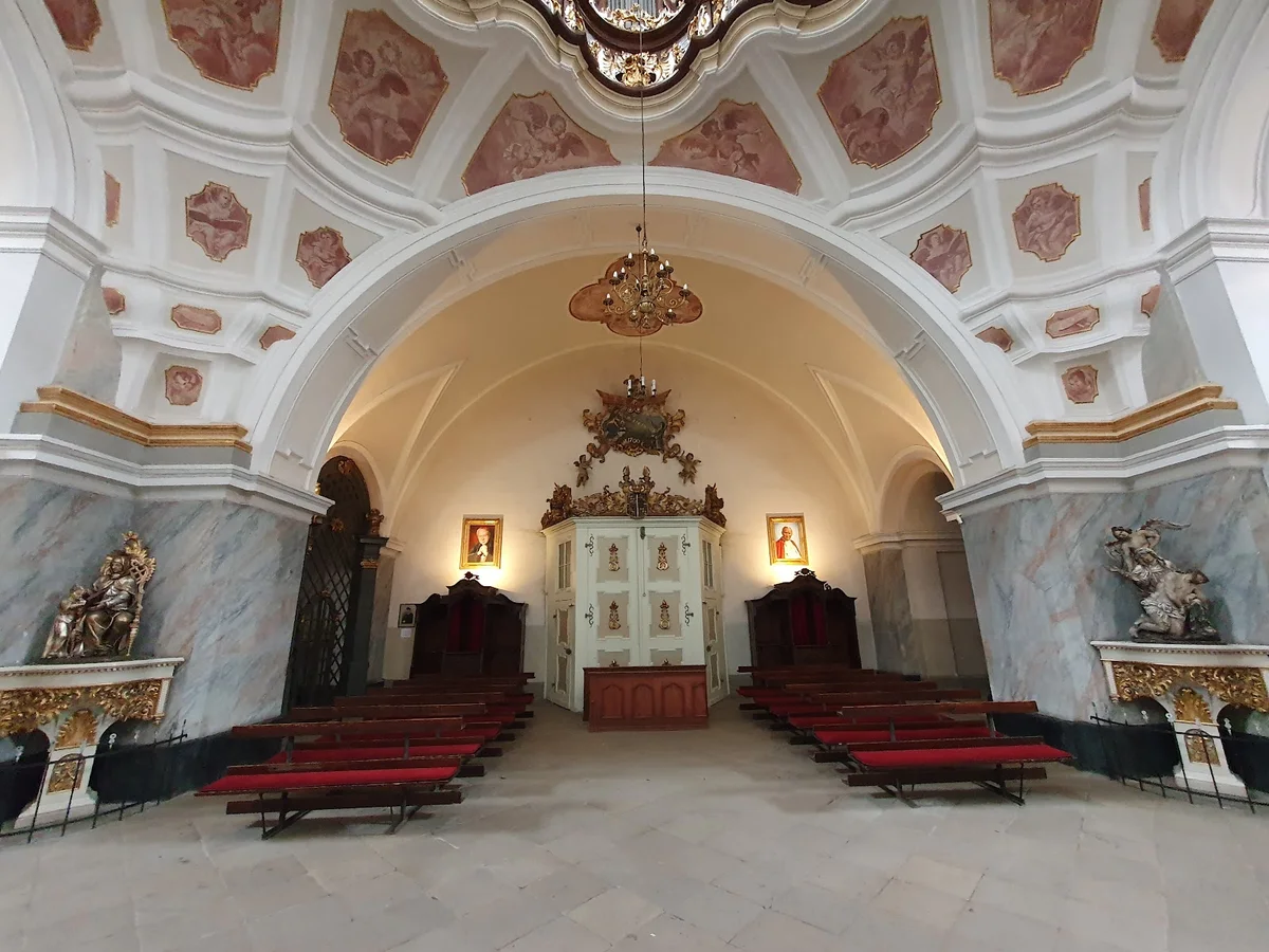 Wnętrze kaplicy z freskami o tradycyjnym wystroju pod słońcem w bieli.