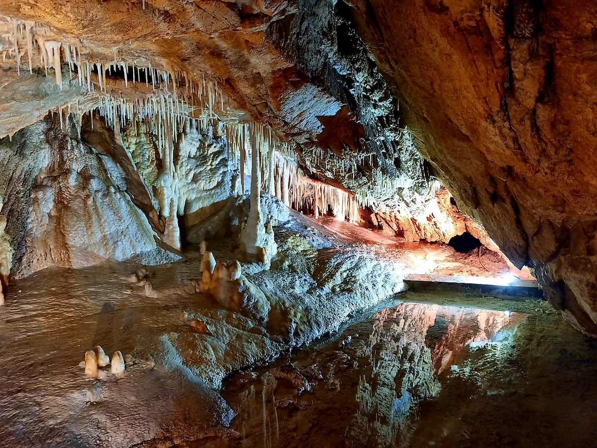 Podświetlone podziemne jezioro w jaskini pod słońcem pod niebem o świcie.