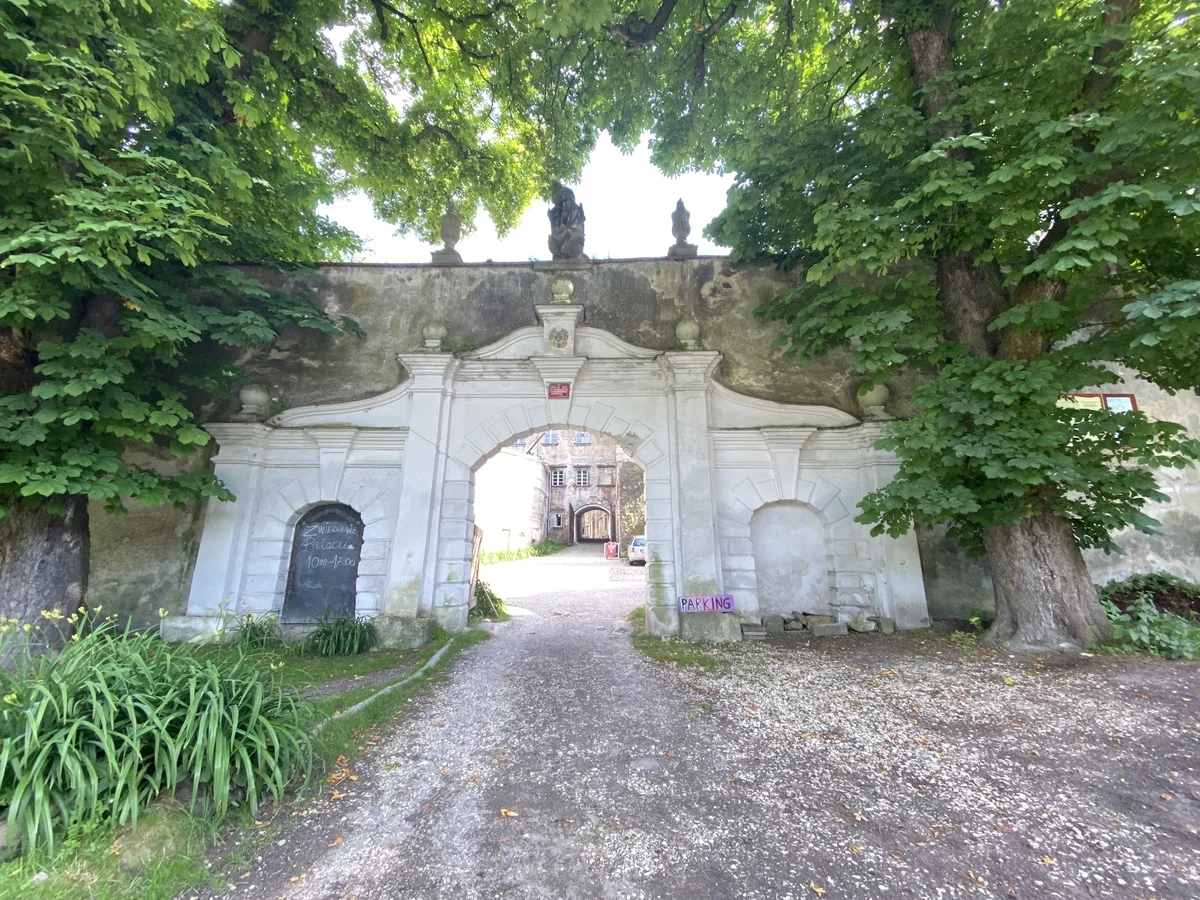 Brama do parku przypałacowego pod błękitnym niebem pod słońcem.