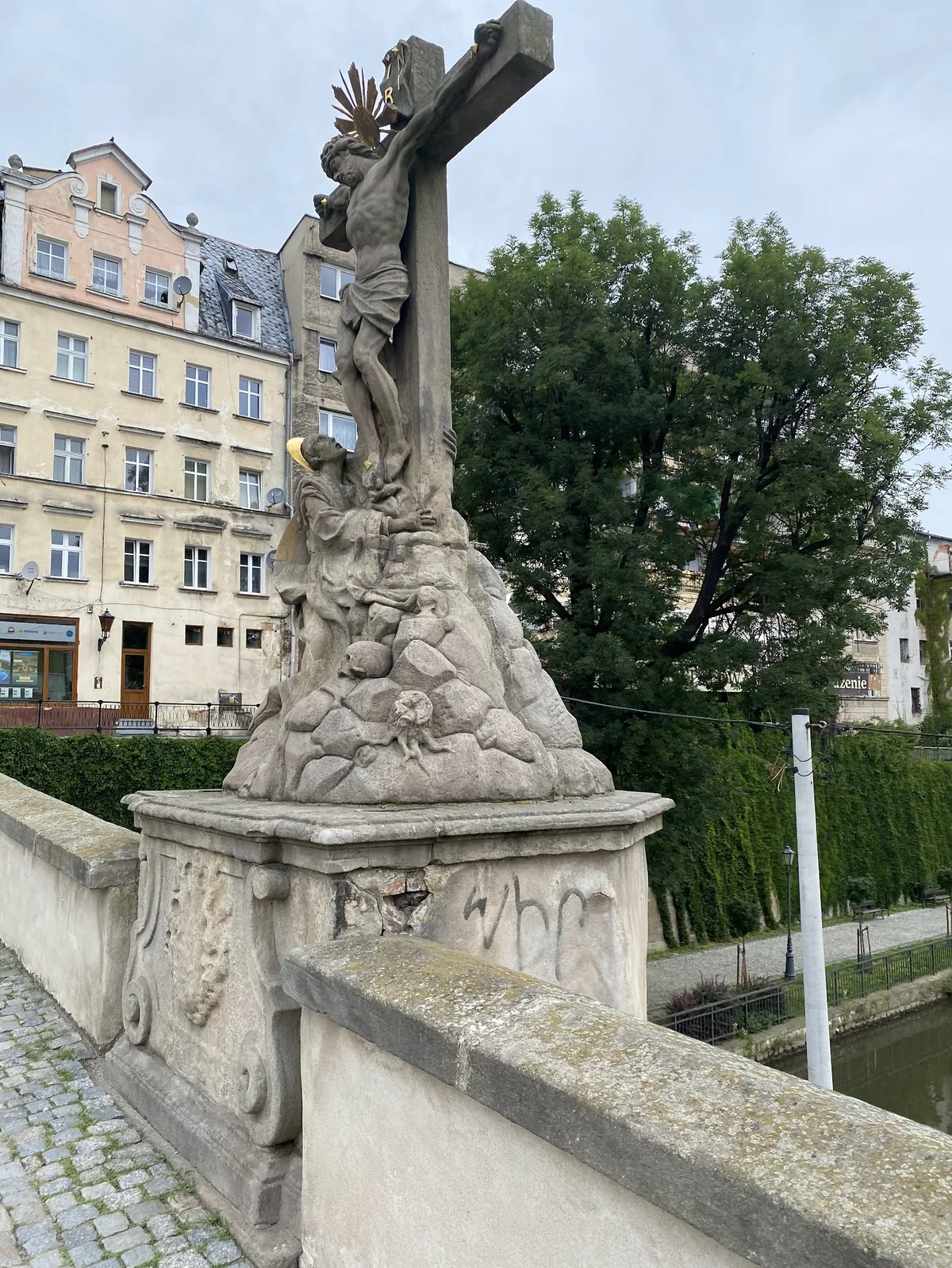 Figura świętego na postumencie o słońcu pod niebem.