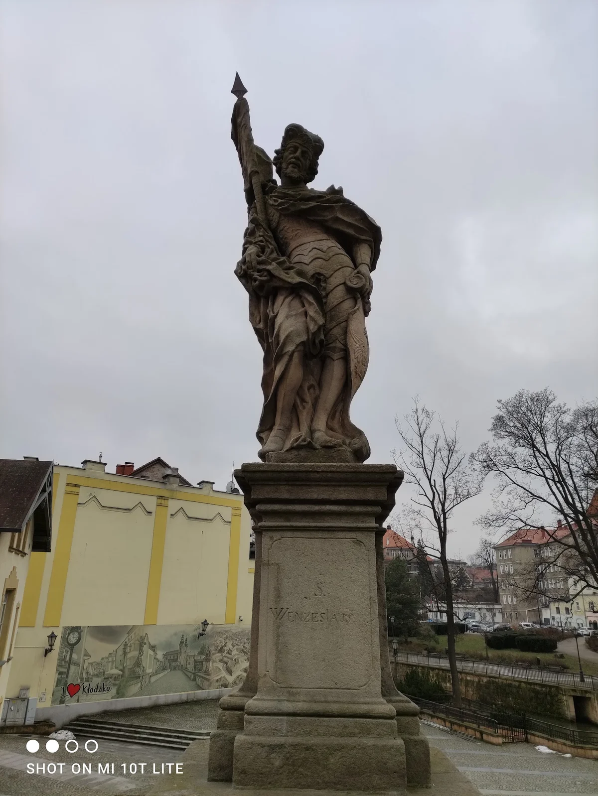 Pomnik świętego na tle zieleni pod błękitnym niebem pod słońcem.