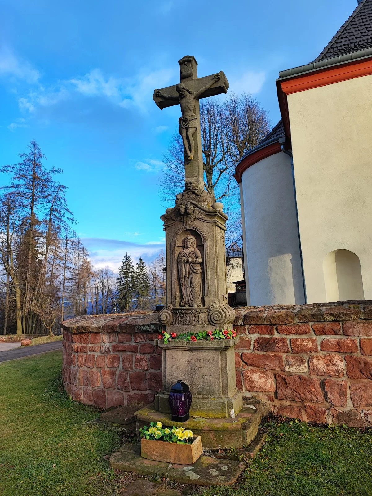 Zabytkowy krzyż na skraju drogi w słońcu.