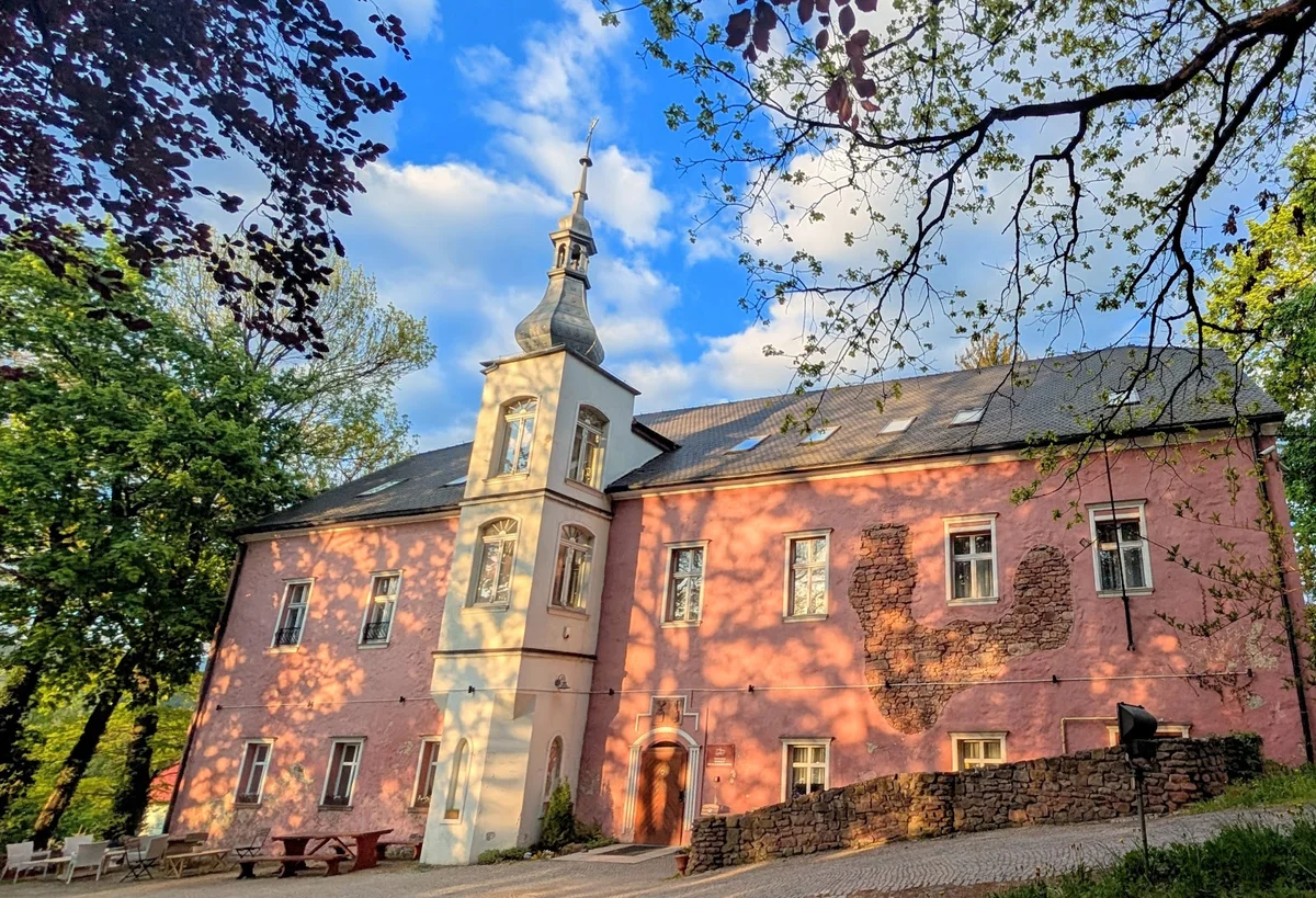Zabytkowa nastrojowa rezydencja z cegły otoczona drzewami letting porą.